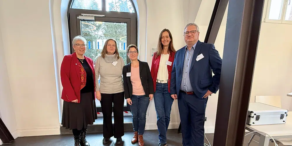 Prof. Dr. Susanne Kröhnert, Prof. Dr. Katharina Gröning, Prof. Dr. Heike Friesel-Wark, Miriam Bredemann und Robert Erlinghagen stehen nebeneinander im Luise-Fliedner-Saal der Fliedner Fachhochschule und lächeln in die Kamera