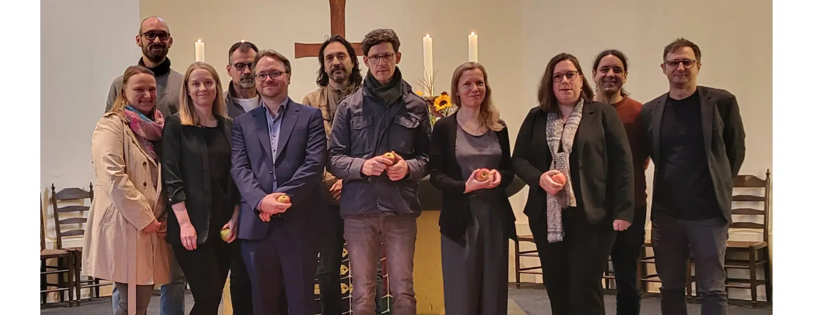 Gruppenfoto in einer Kirche mit mehreren Erwachsenen vor einem Altar mit Kerzen.